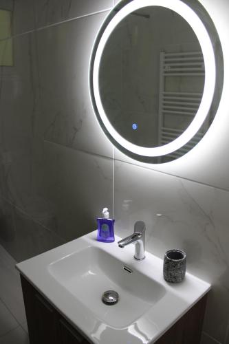 a bathroom sink with a round mirror above it at Ολόκληρο Διαμέρισμα η Βυσσινιά in Kotrónion