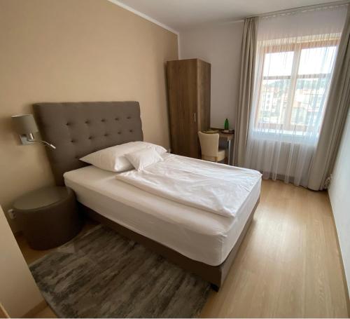 a bedroom with a bed with white sheets and a window at Hotel MAGISTR Vsetín in Vsetín