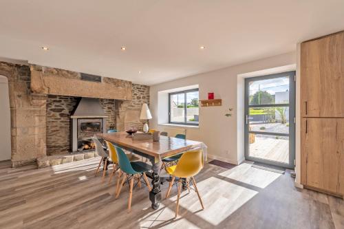 une salle à manger avec une table et des chaises et une cheminée dans l'établissement À la maison de Goulannou, à Tréflez