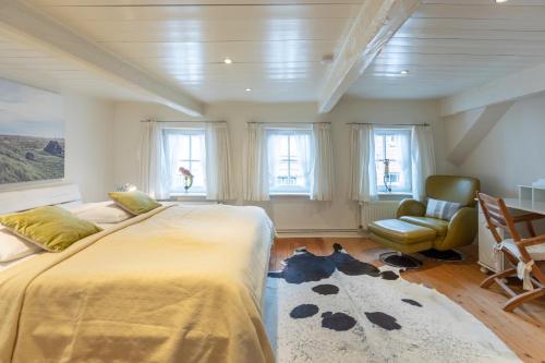 a bedroom with a large bed and a chair and windows at Dat witte Huus in Husum