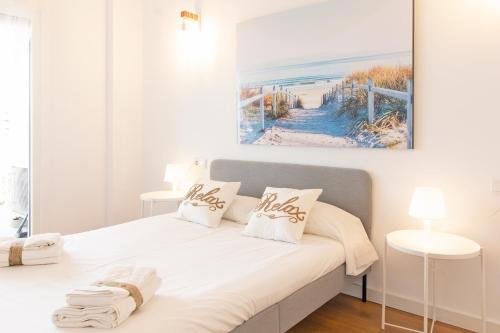 um quarto com uma cama branca e uma pintura na parede em Global Properties, Moderno apartamento en Canet al Mar em Canet d'En Berenguer