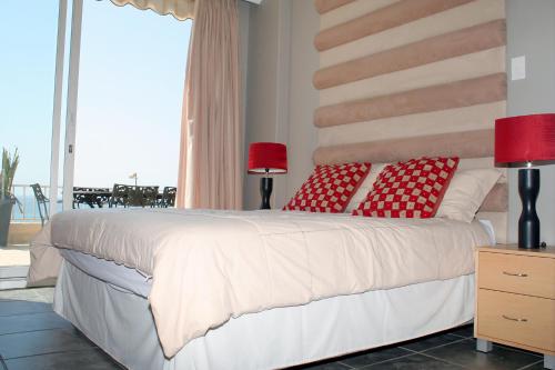 a bedroom with a large white bed with red pillows at 204 Marbella Umhlanga in Durban