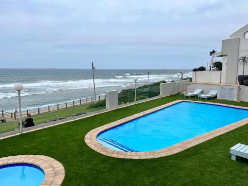 a swimming pool with the ocean in the background at 204 Marbella Umhlanga in Durban