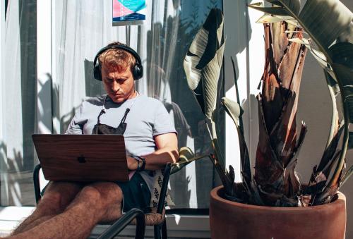 a man wearing headphones sitting in a chair with a laptop at Selina Boavista Ericeira in Ericeira