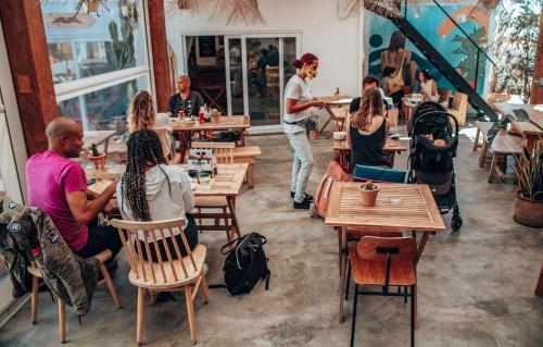 un grupo de personas sentadas en mesas en un restaurante en Selina Boavista Ericeira, en Ericeira