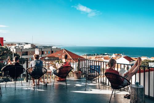 eine Gruppe von Personen, die auf einem Balkon mit Meerblick sitzen in der Unterkunft Selina Boavista Ericeira in Ericeira