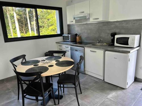 een keuken met een tafel en stoelen en een magnetron bij Appartement Le Mans proche du circuit des 24h in Changé