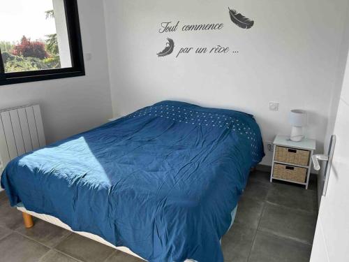 a bedroom with a blue bed with a sign on the wall at Appartement Le Mans proche du circuit des 24h in Changé
