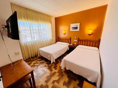a hotel room with two beds and a television at Tortosa Parc in Tortosa
