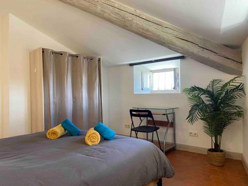 une chambre avec un lit avec des oreillers bleus et jaunes dans l'établissement Appartement de charme au cœur d'Avignon, à Avignon