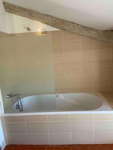 La salle de bains est pourvue d'une baignoire blanche et de carrelage. dans l'établissement Appartement de charme au cœur d'Avignon, à Avignon