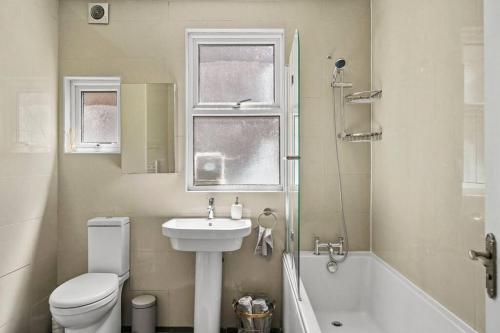 a bathroom with a sink and a toilet and a tub at Bright 2 Bed Perfect Central Hub in London