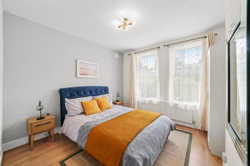 a bedroom with a bed with a blue headboard and two windows at Bright 2 Bed Perfect Central Hub in London