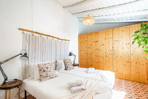 una camera con un letto bianco e una parete in legno di BeGuest Casa Romãzeira Typical Vila ad Alfarrobeira