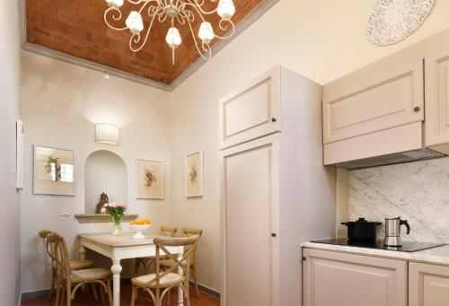 a kitchen with white cabinets and a table with chairs at Borgo Antico Casalbosco Holiday Home & Winery in Santomato 