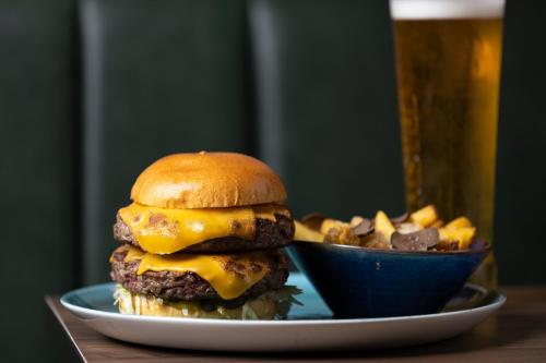 a cheeseburger on a plate with a bowl of fries at Holiday Inn London Gatwick - Worth by IHG in Crawley