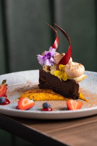 a piece of chocolate cake with flowers on a plate at Holiday Inn London Gatwick - Worth by IHG in Crawley