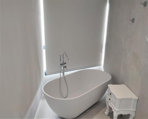 a white bathroom with a tub and a toilet at Light Blue Hotel in Nea Kalikratia
