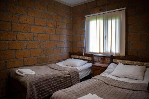 1 dormitorio con 2 camas y pared de ladrillo en Noravank L-and-L, en Namazalu