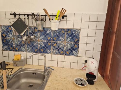 een aanrecht met een wastafel en een tegelwand bij Casette di Alex con TERRAZZA in Trapani