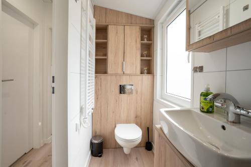 een badkamer met een toilet, een wastafel en een raam bij Ostseecamp Ferienhaus "Koralle" in Scharbeutz