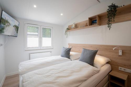 - une chambre avec un grand lit blanc et 2 oreillers dans l'établissement Ostseecamp Ferienhaus "MeeresRauschen", à Scharbeutz