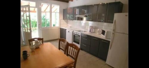 une cuisine avec une table et un réfrigérateur blanc dans l'établissement Les Roseries Boutique Gite, à Clussais-la-Pommeraie