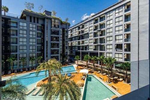 an apartment complex with a swimming pool and palm trees at Tropics Kamala Deluxe Pool View Apartment CTG P402 in Kamala Beach