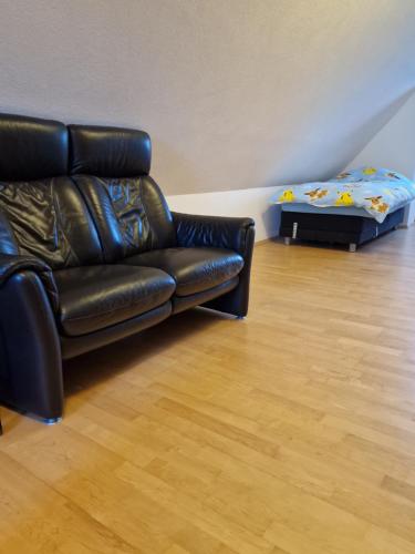 sala de estar con sofá de cuero negro y cama en Pension im Grünen 