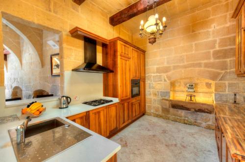 - une cuisine avec des placards en bois et un mur en pierre dans l'établissement Dar il-Wied Farmhouse, à L-Għarb