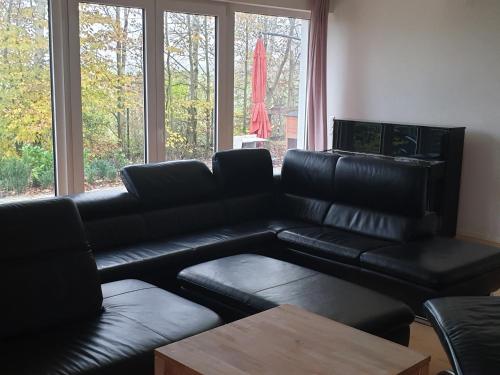 sala de estar con sofá de cuero negro y mesa en Pension im Grünen 