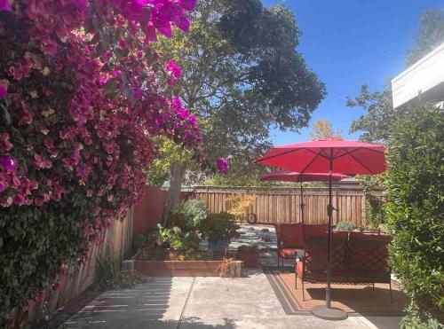 a patio with a red umbrella and a fence with flowers at Palo Alto Quiet 1 Bedroom Stanford University in Palo Alto