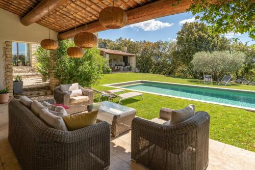 un patio avec des chaises et une table ainsi qu'une piscine dans l'établissement Villa Les Terrasses de Gordes, à Gordes