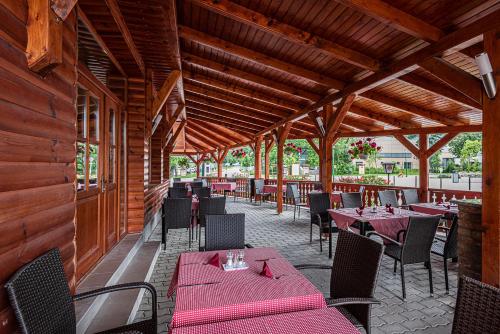 a restaurant with tables and chairs in a building at Gasthaus Panzió in Szilvásvárad