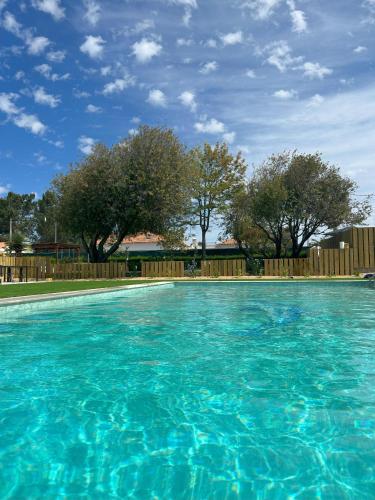 a large blue swimming pool with a wooden fence at Quinta da Boavista in Vila Nova de Milfontes