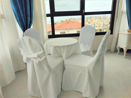 a white table and chairs in a room with a window at Light Blue Hotel in Nea Kalikratia