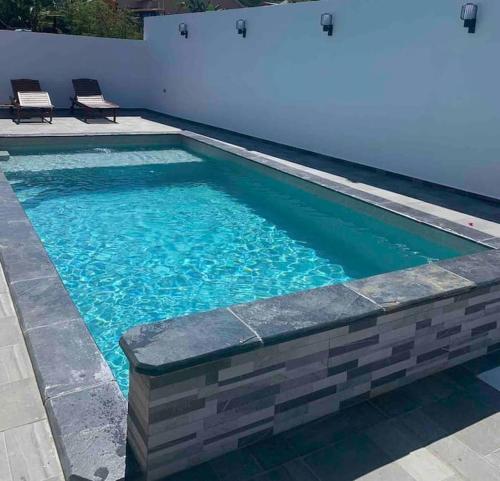 - une piscine d'eau bleue et 2 chaises dans l'établissement Villa Fleurs de Cannes 4*, à Saint-Louis