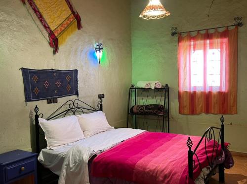 a bedroom with a bed with a red and pink blanket at Merzouga Camp and Hostel in Merzouga
