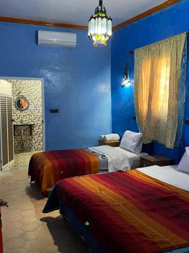 a blue bedroom with two beds and a chandelier at Merzouga Camp and Hostel in Merzouga