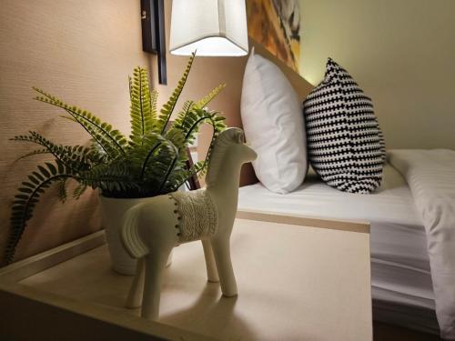 a table with a plant and a lamp and a bed at บ้านสุขใจ สามใบเถา in Ban Kluai