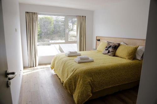 a bedroom with a yellow bed with a window at Gente del Sur - Cinco Hermanos in Ushuaia