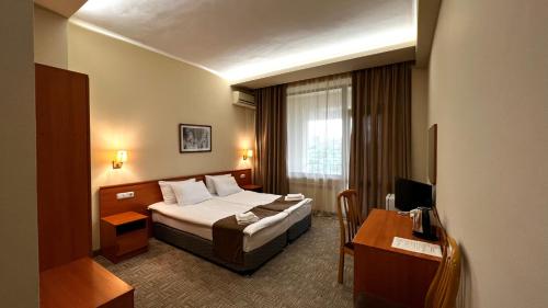 Olympia Garden Hotel في يريفان: غرفة في الفندق مع سرير ومكتب