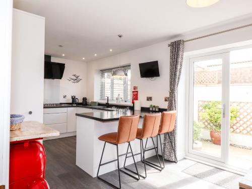 a kitchen with white cabinets and a bar with stools at Seagull Shack in Porthmadog