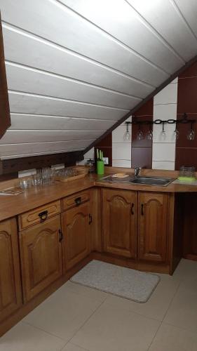 a kitchen with wooden cabinets and a white ceiling at Apartament Huba in Huba