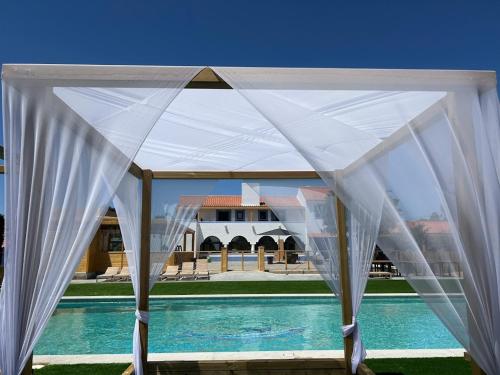 a white canopy over a swimming pool in front of a building at Quinta da Boavista in Vila Nova de Milfontes
