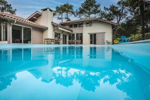 une maison avec une piscine devant une maison dans l'établissement Emachethaco - Location vacances hossegor superbe villa de standing avec jardin et piscine chauffée, à Soorts-Hossegor