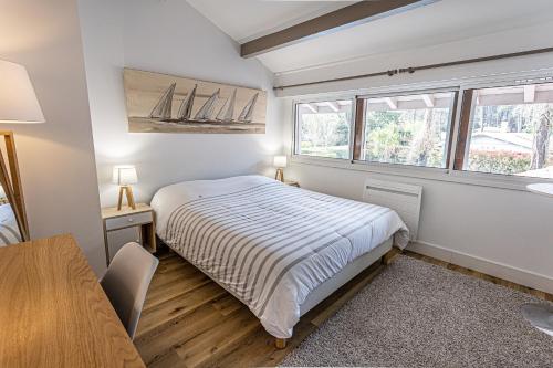 une chambre avec un lit et une table et deux fenêtres dans l'établissement Emachethaco - Location vacances hossegor superbe villa de standing avec jardin et piscine chauffée, à Soorts-Hossegor