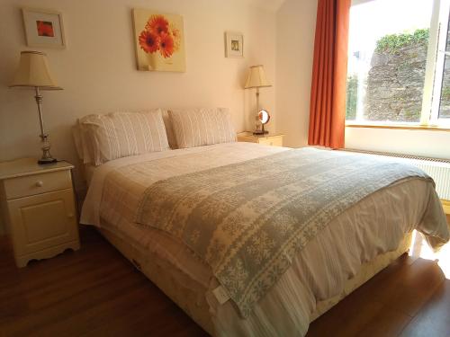 Un dormitorio con una cama grande y una ventana en Church Street Cottage, en Rosscarbery