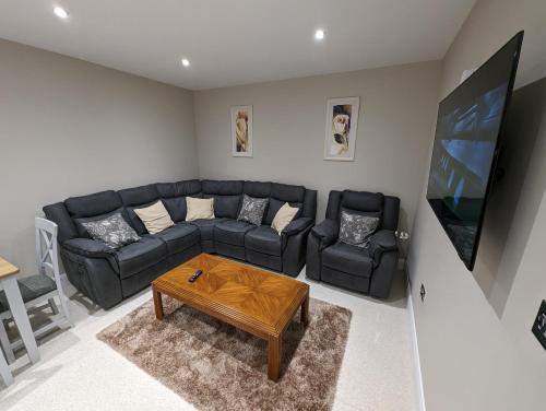 sala de estar con sofá negro y TV en Derg Valley Apartments, en Castlederg