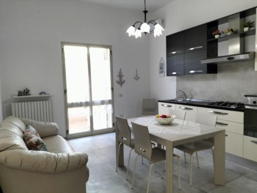 a kitchen and dining room with a table and a couch at Casa sole e luna in Porto Cesareo